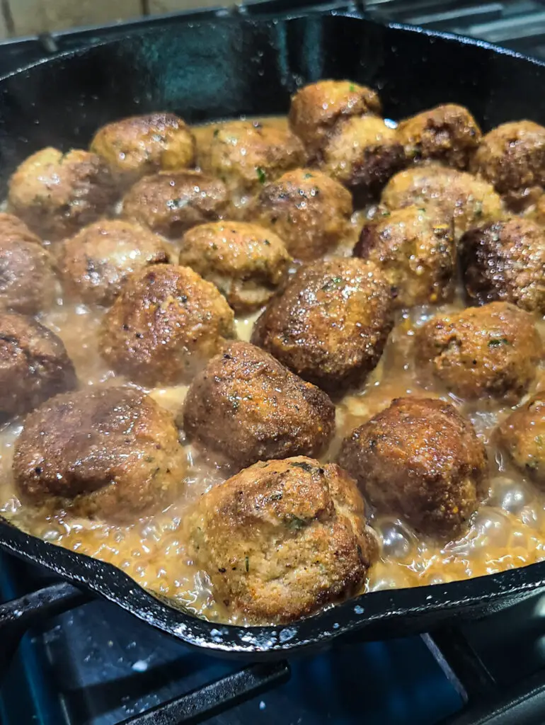cast iron pan with seared chicken piccata meatball in lemon sauce