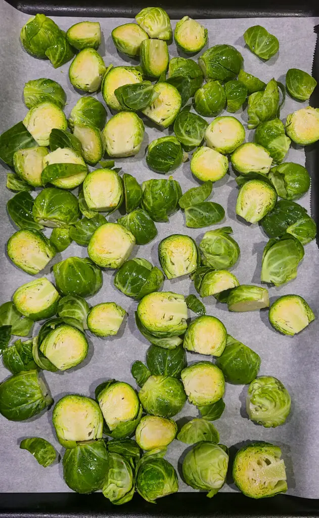 raw halved brussels sprouts on parchment lined baking sheet