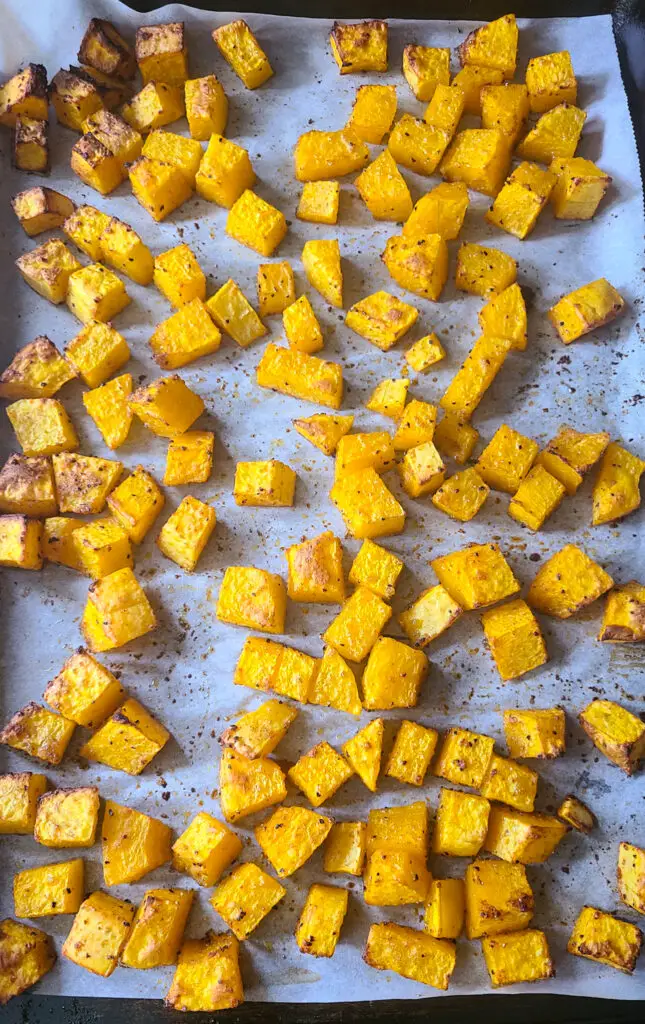 roasted cubed butternut squash on parchment lined baking sheet