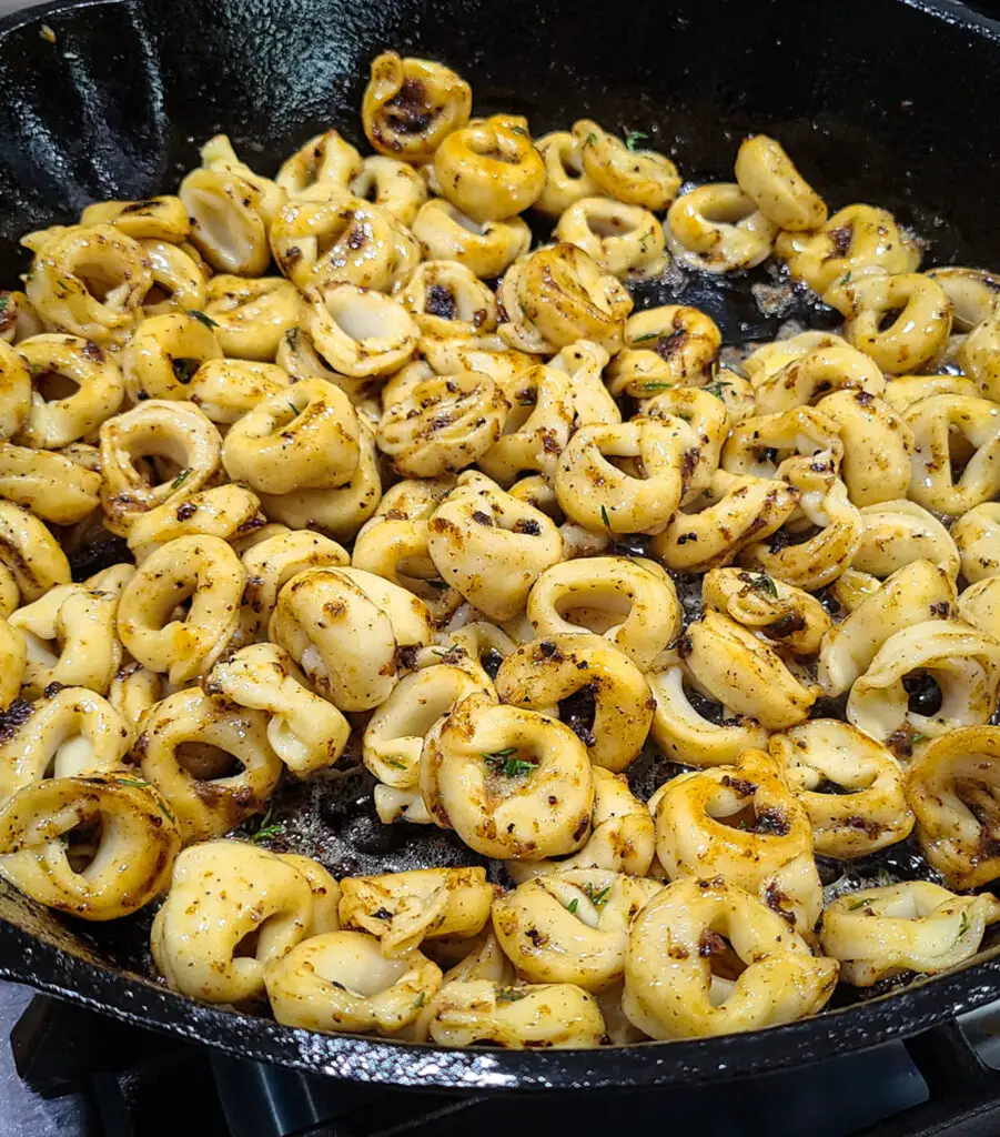 cheese tortellini in cast iron pan toss with a flavorful browned butter garlic sauce and fresh thyme leaves.