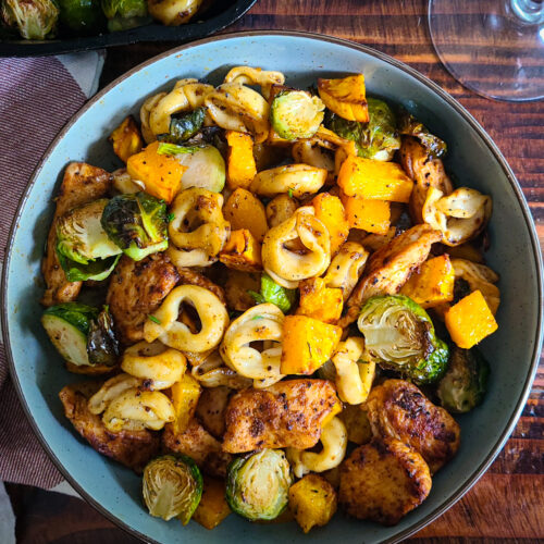 overhead image of Chicken and Tortellini with Autumn Roasted Vegetables next to linen napkin to the left and a fork to the right.