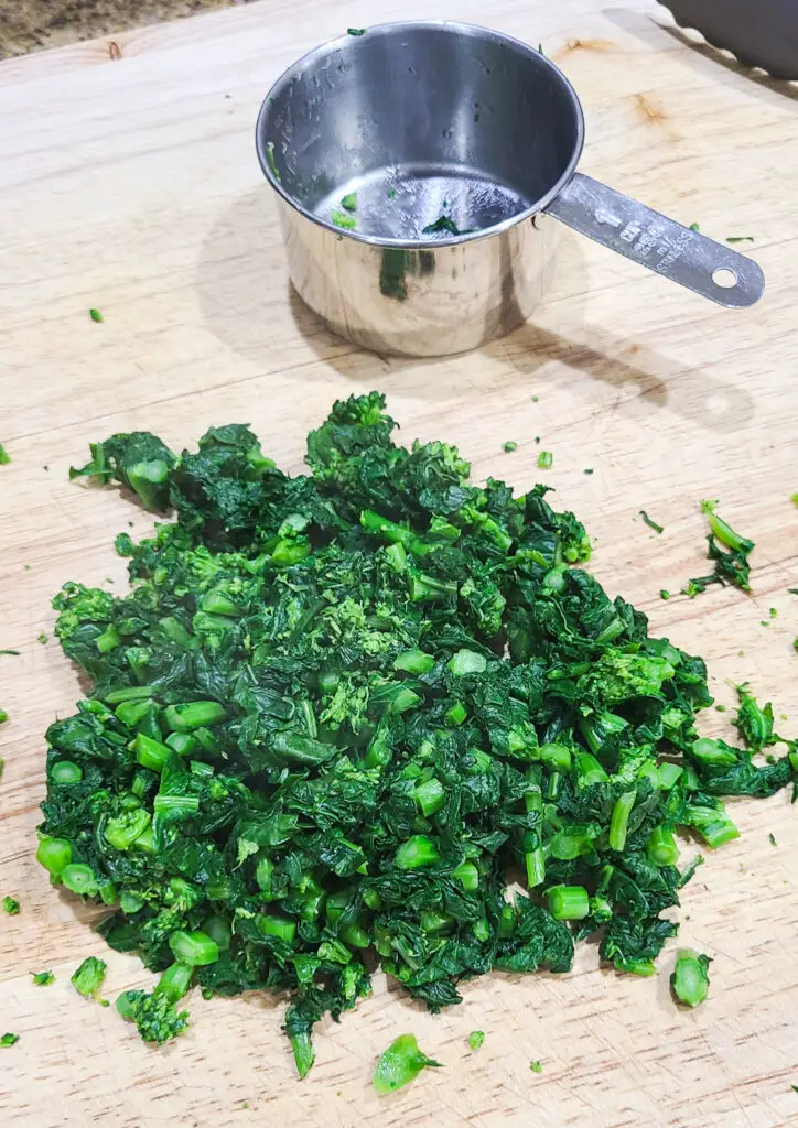 chopped cooked broccoli rabe on wooded cutting board