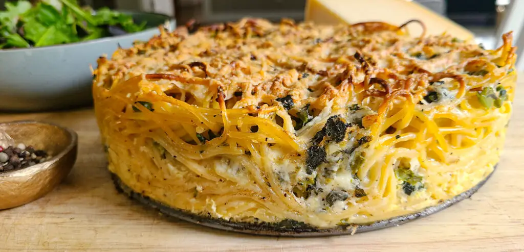 side angle upclose image of spaghetti frittata pie with a crunchy browned top and sides