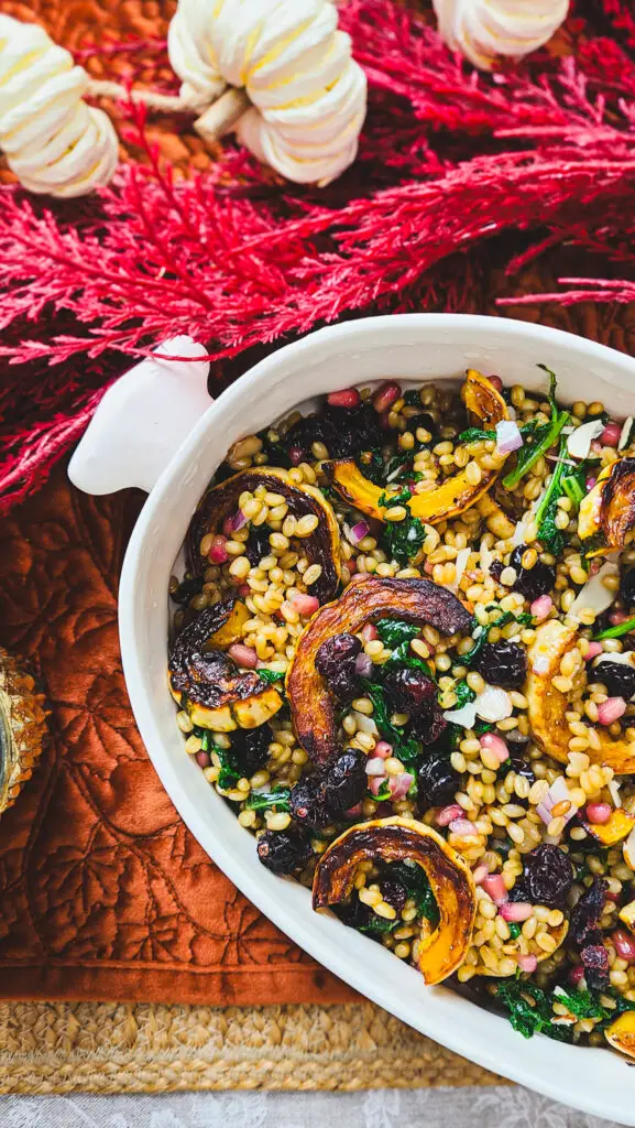 image of wheat berry salad with roasted squash and kale set on a table with autumnal themed tablescape