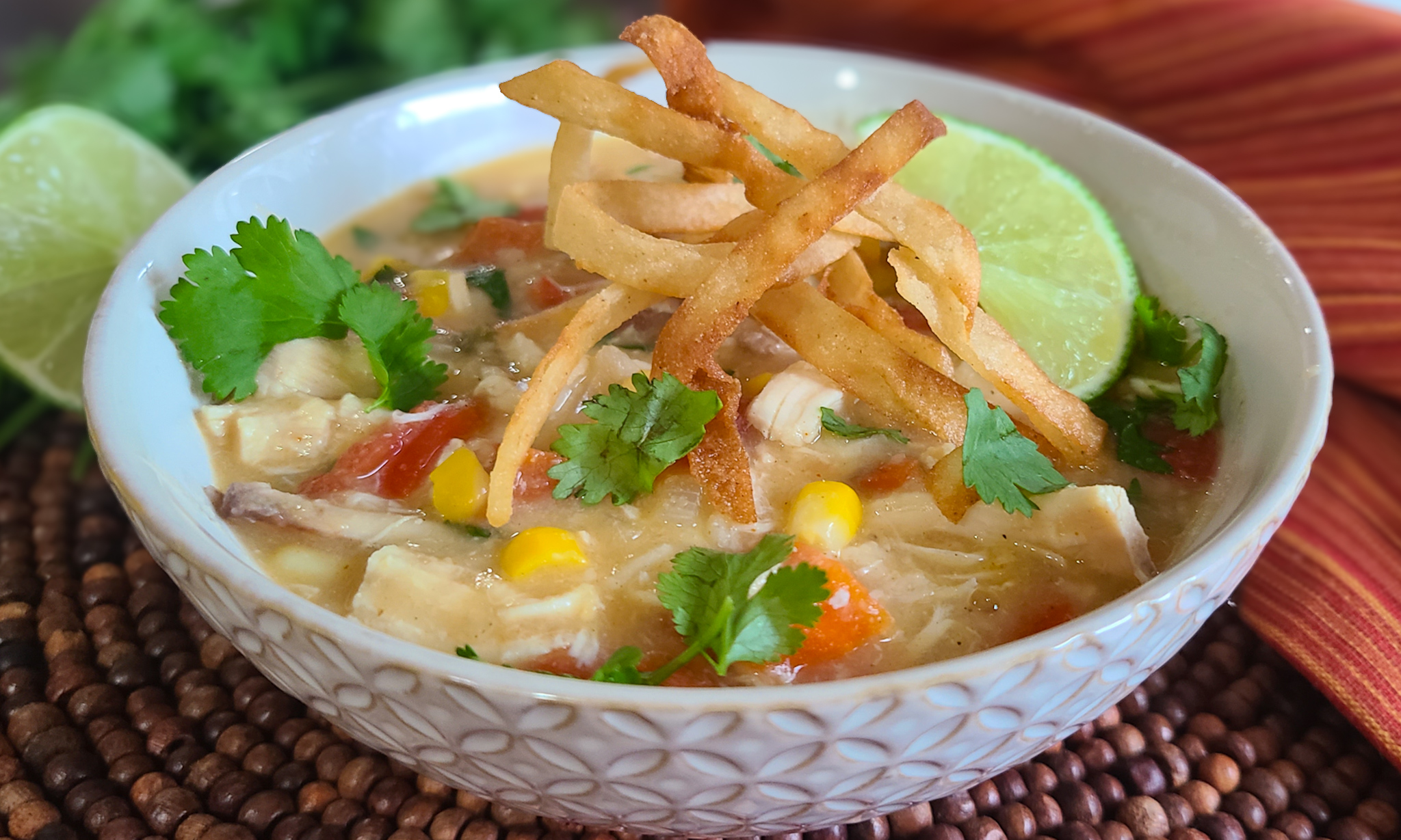 image of bowl of chicken tortilla soup with tortilla strips and lime as garnish